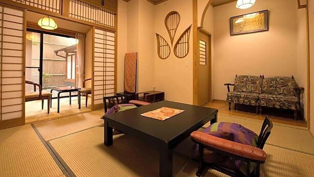 Perinteinen japanilaistyylinen huone, jossa on tatamimatto, matala pöytä tyynyineen ja sohva.