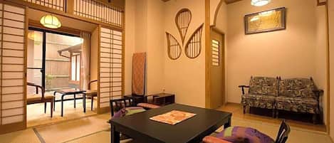 A traditional Japanese-style room with tatami flooring, a low table with cushions, and a sofa.