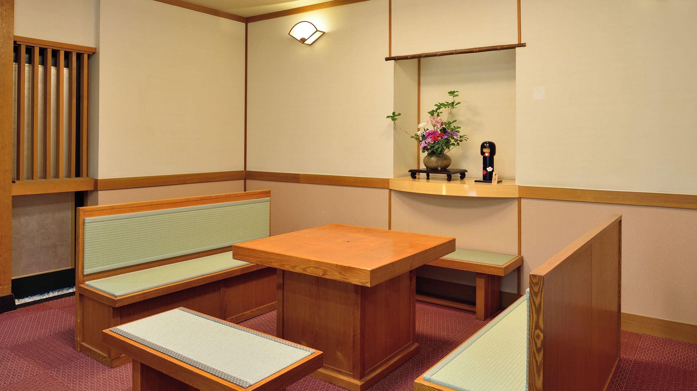 Una habitación tradicional japonesa con suelo de tatami, una mesa de madera baja y asientos.