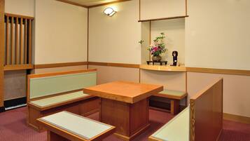 Una habitación tradicional japonesa con suelo de tatami, una mesa de madera baja y asientos.