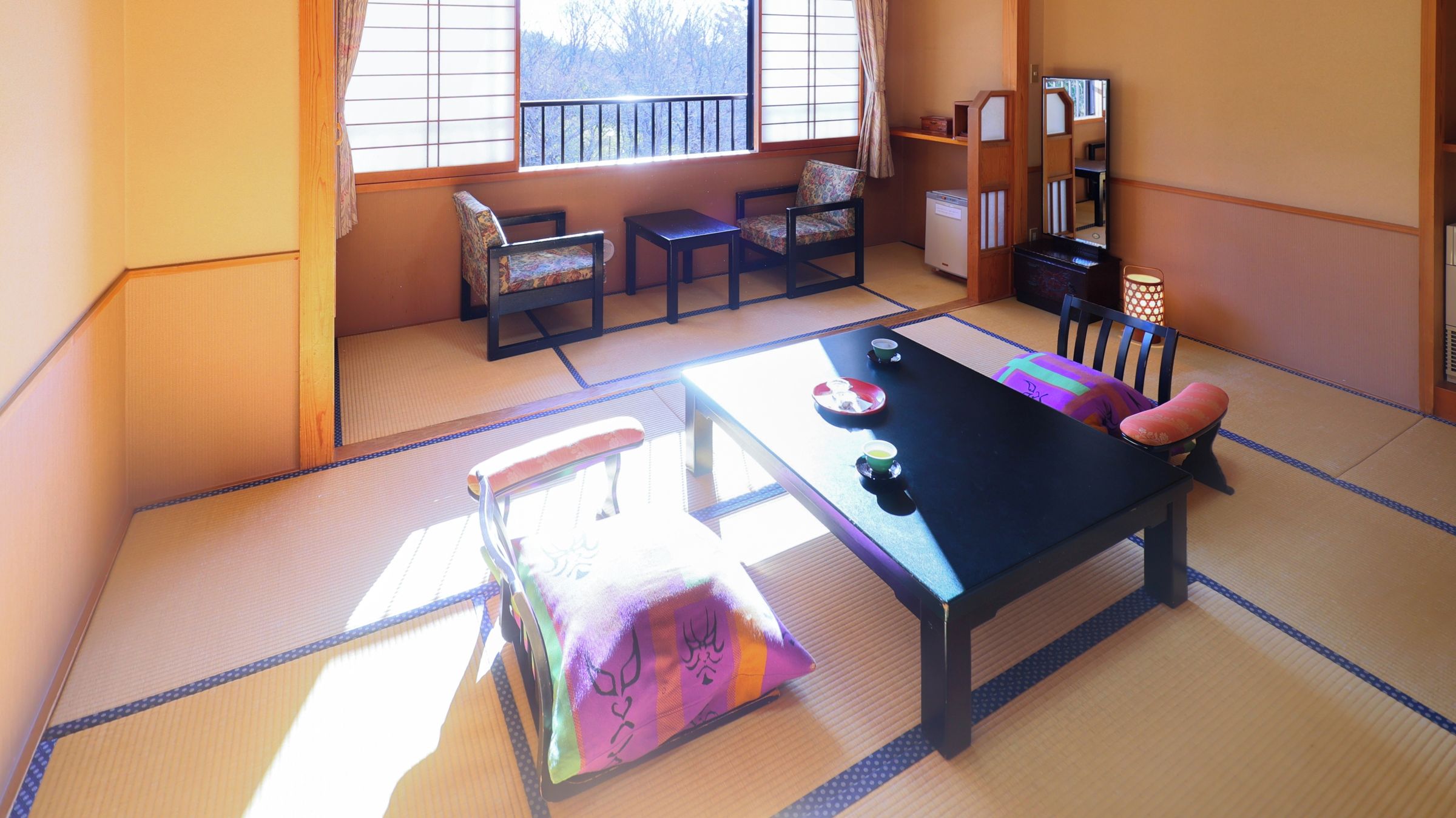 Una habitación con tatamis, una mesa baja, sillas y un armario japonés tradicional.
