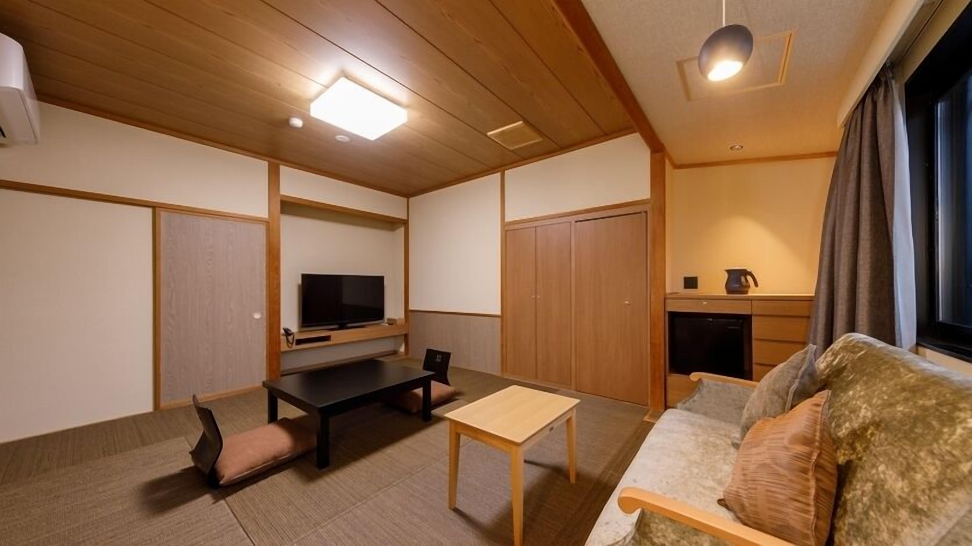 A compact living space with a sofa, a small table, a TV, and a kitchenette.