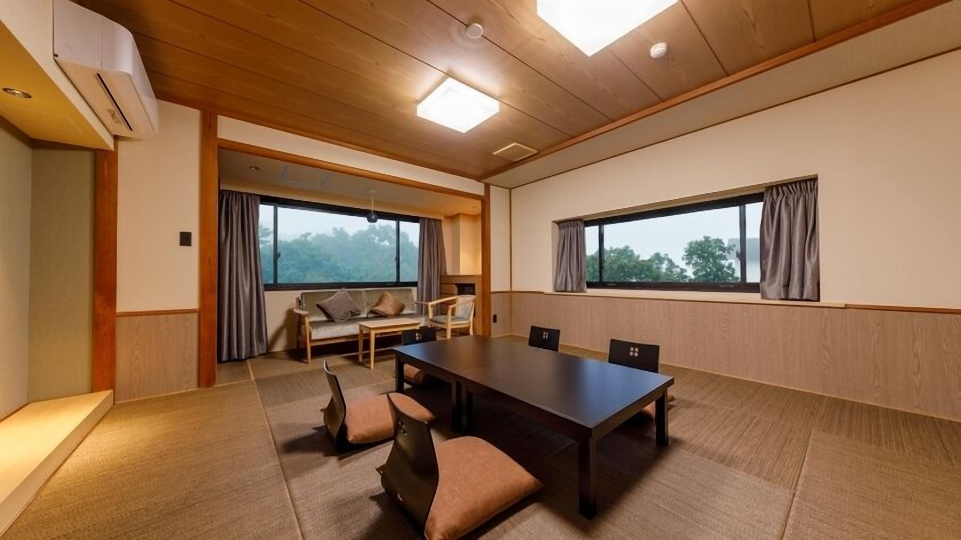 A conference room with a long table, four chairs, a sofa, and two windows with curtains.