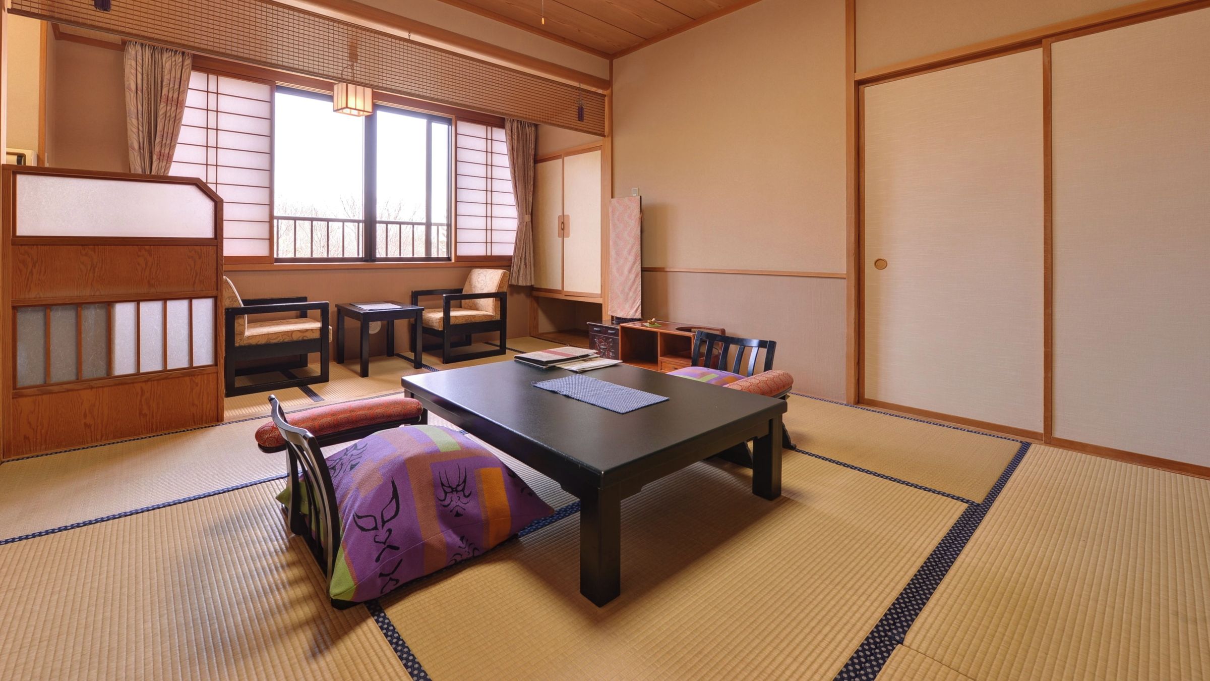 Una habitación japonesa tradicional con suelo de tatami, una mesa baja y un sofá.