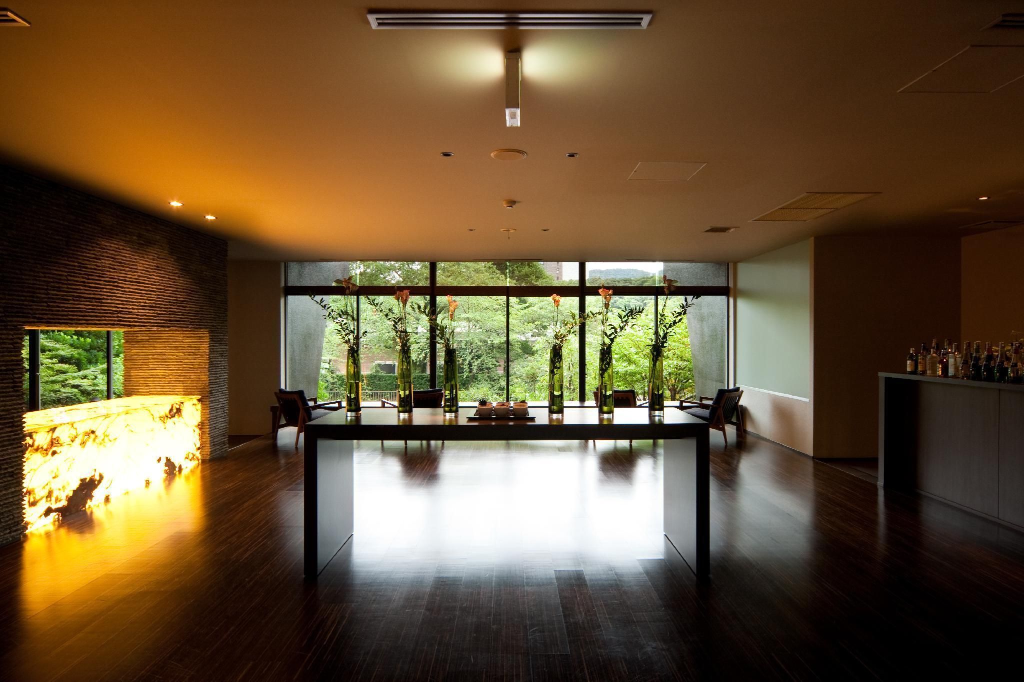 A modern interior with a long table, large windows, and a fireplace.