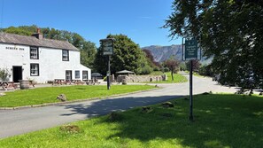 Un bâtiment blanc portant l’inscription « Screes Inn », avec des places assises à l’extérieur et un mur en pierre.
