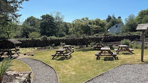 A garden with picnic tables and a stone wall. - The Strands & Screes Inn (Seascale)