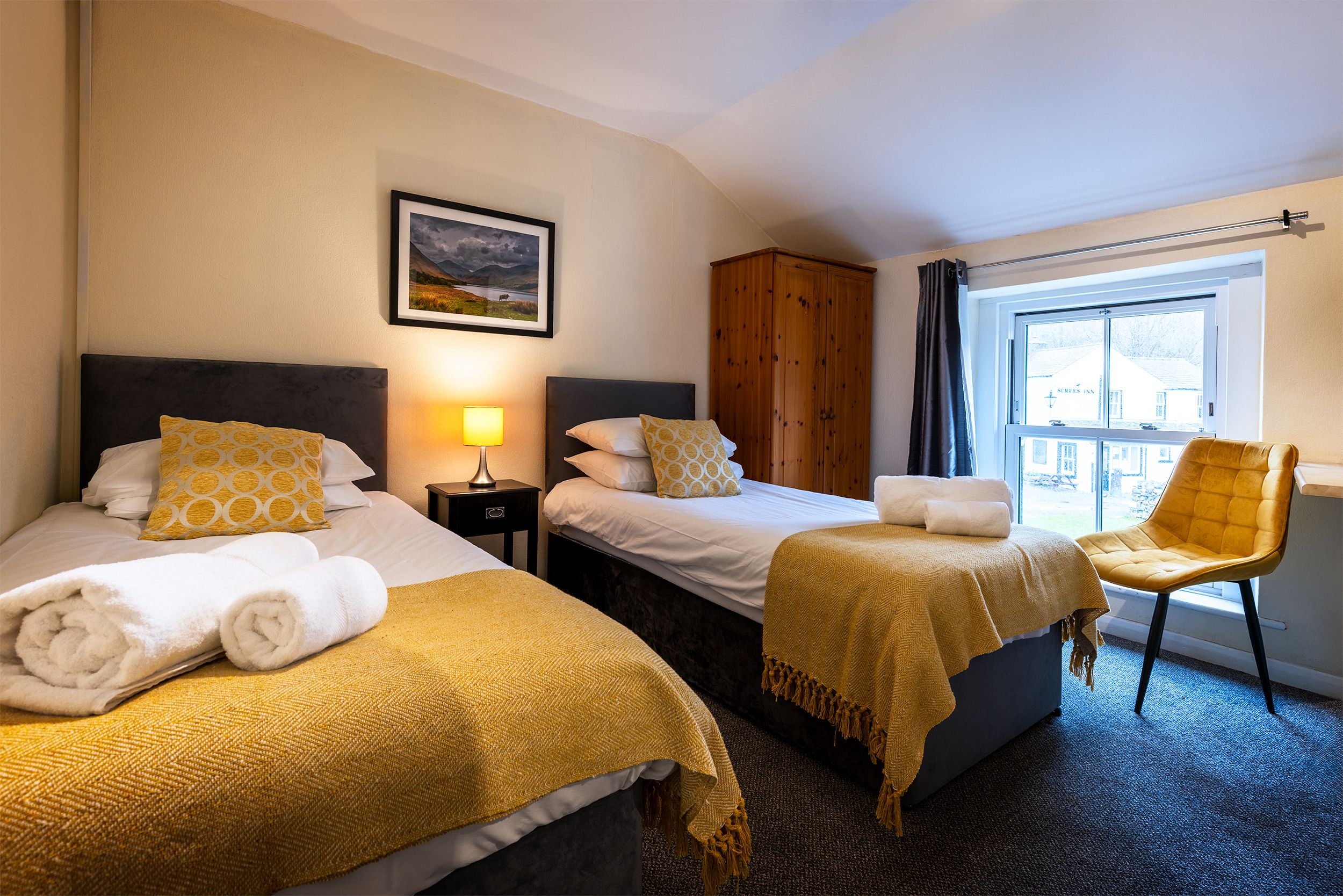 Une chambre d’hôtel avec deux lits, une armoire, une chaise et une fenêtre.