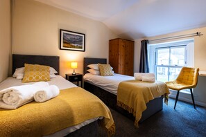 Une chambre d’hôtel avec deux lits, une armoire, une chaise et une fenêtre.