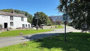 A white building labeled 'Screes Inn' with outdoor seating and a stone wall. - The Strands & Screes Inn (Seascale)