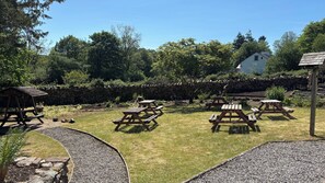 Un jardin avec des tables de pique-nique et un mur en pierre.