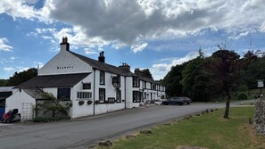A traditional white building with a sign reading 'Strands Inn' and a sign for a brewery. - The Strands & Screes Inn (Seascale)