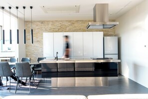 A modern kitchen with a central island, a dining area with chairs, and pendant lights.
