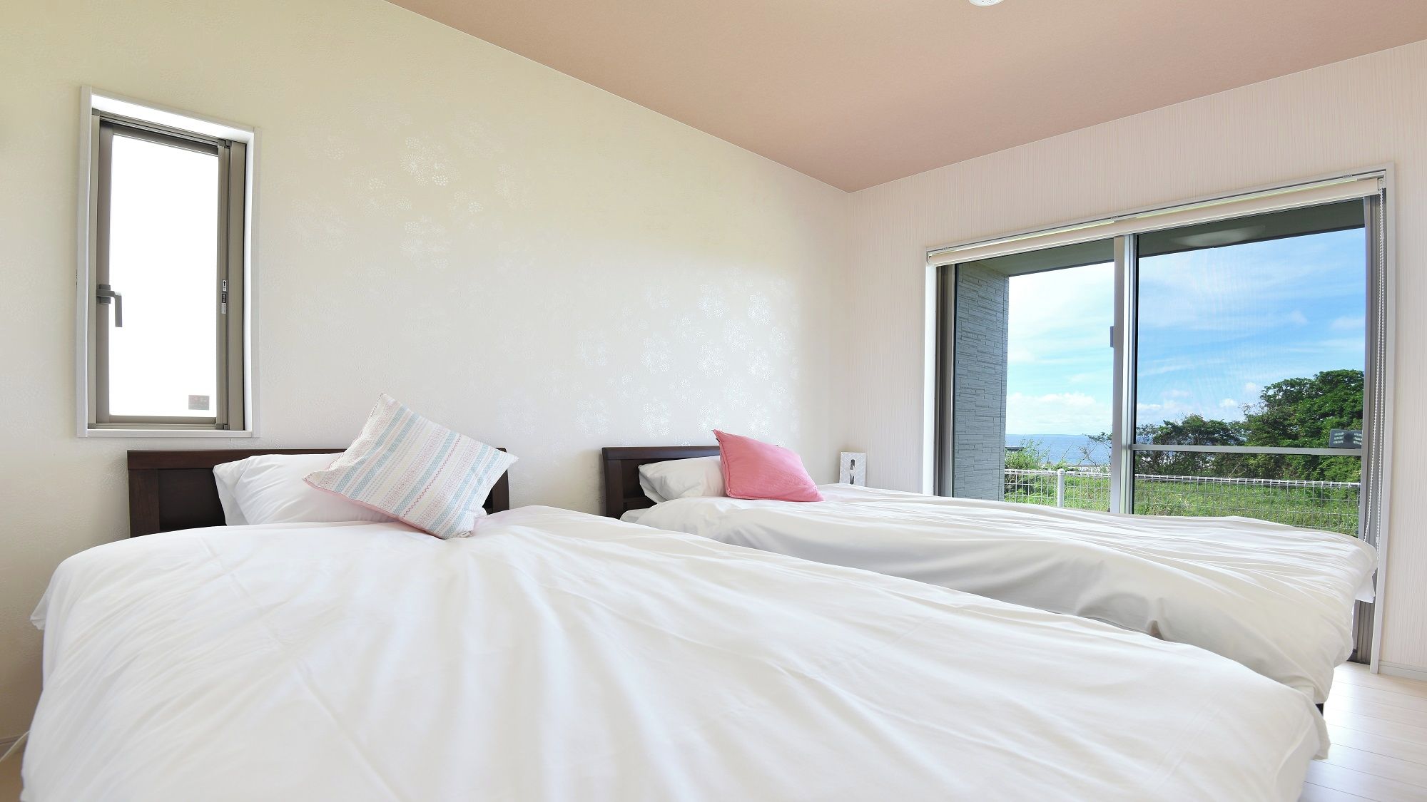 A bedroom with two beds, a large window, and a view of the outdoors.