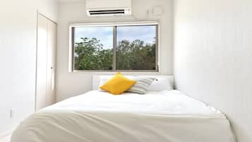 A bedroom with a bed, a window, and an air conditioning unit.