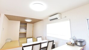 A room with a whiteboard, air conditioning unit, and a table with chairs. - Villa Charme (Motobu)