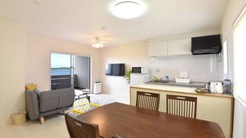 A compact living space with a kitchenette, a dining area, and a balcony with a view.