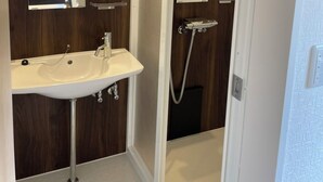 A bathroom with a sink, mirror, and shower. - Sunset Resort Kanutan (Motobu)