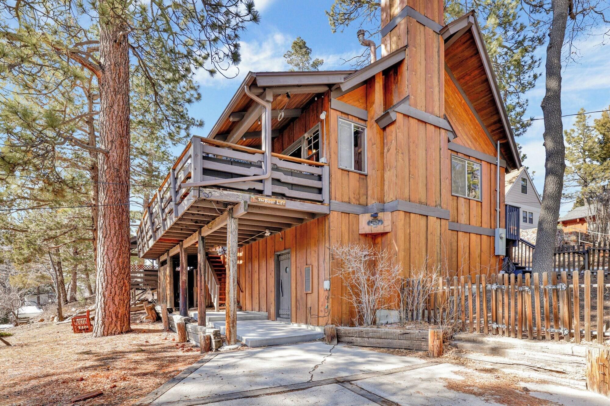 A wooden cabin with a balcony, surrounded by trees.