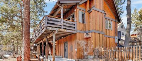 A wooden cabin with a balcony, surrounded by trees.