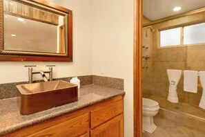 A bathroom with a wooden vanity, a copper sink, a mirror, a shower with glass doors, and a toilet. - La Cerena Getaway #1960 (Big Bear Lake)