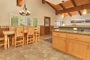A spacious kitchen with wooden cabinets, a granite countertop, and a dining area with wooden chairs. - La Cerena Getaway #1960 (Big Bear Lake)
