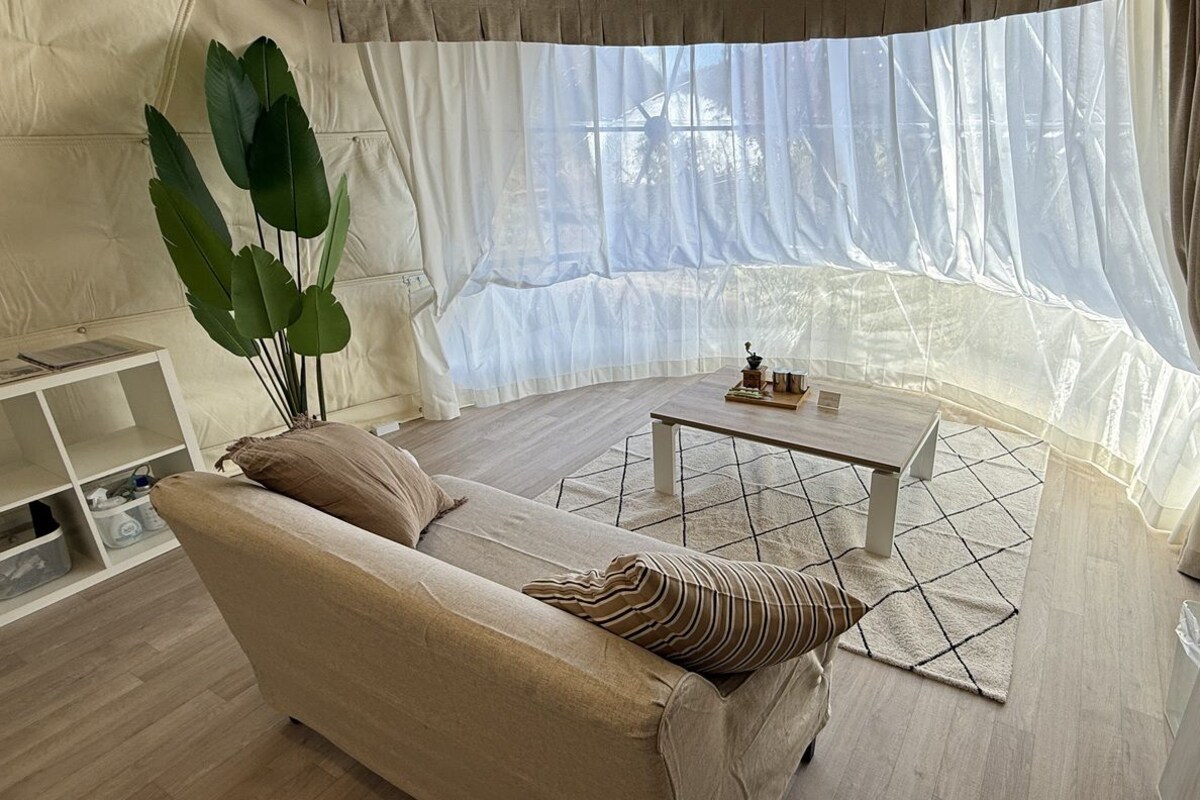 Ein Wohnzimmer mit einem beigen Sofa, einem Couchtisch und einer großen Pflanze.
