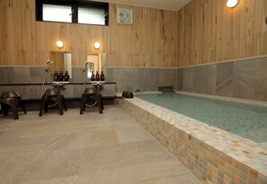 Ein modernes Badezimmer mit einer Holzvertäfelung, einem großen Spiegel, einem Waschbecken und einem kleinen Pool.