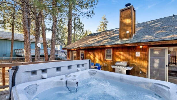 A hot tub with a wooden deck, a barbecue grill, and a wooden cabin with a chimney. - Little Cubs Cabin #1986 (Big Bear Lake)