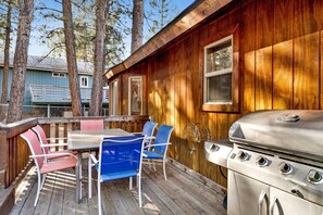 Eine Terrassenausstattung mit Grill, Tisch und Stühlen.