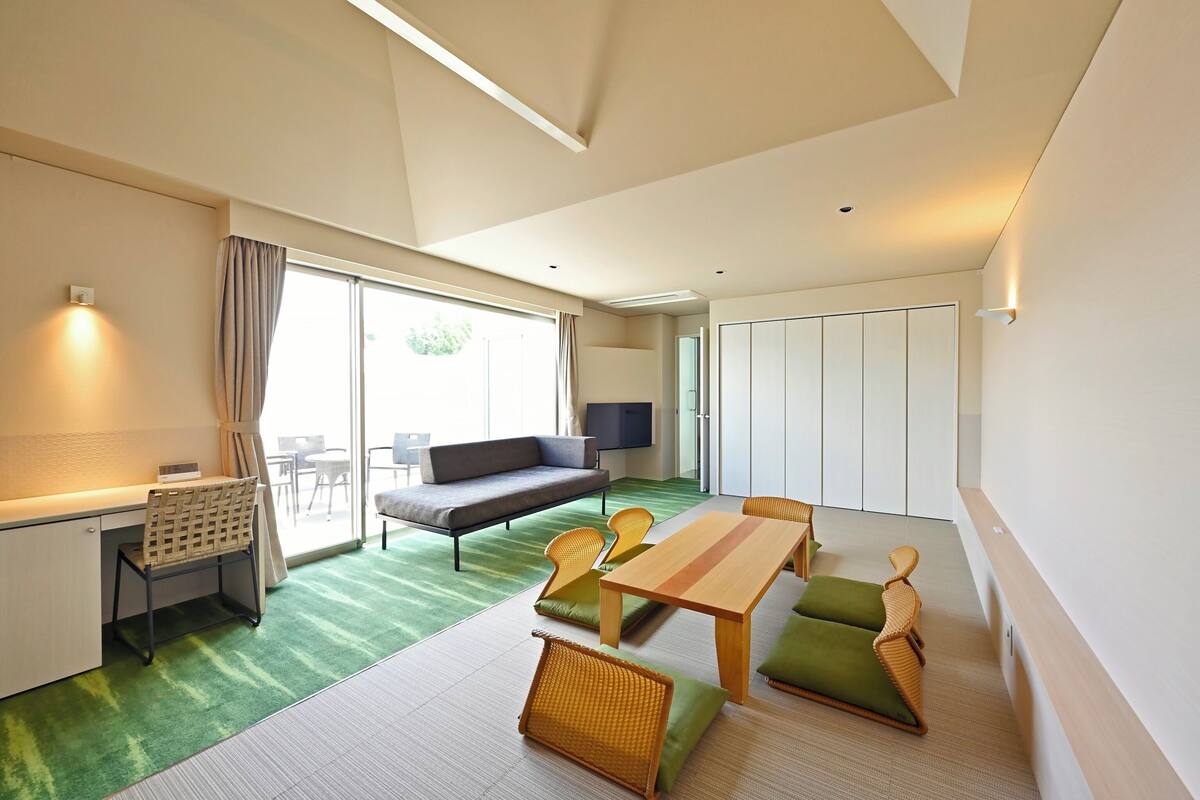 Une chambre d’hôtel moderne équipée d’un canapé, d’une table à manger, de chaises, d’un bureau et d’une télévision.