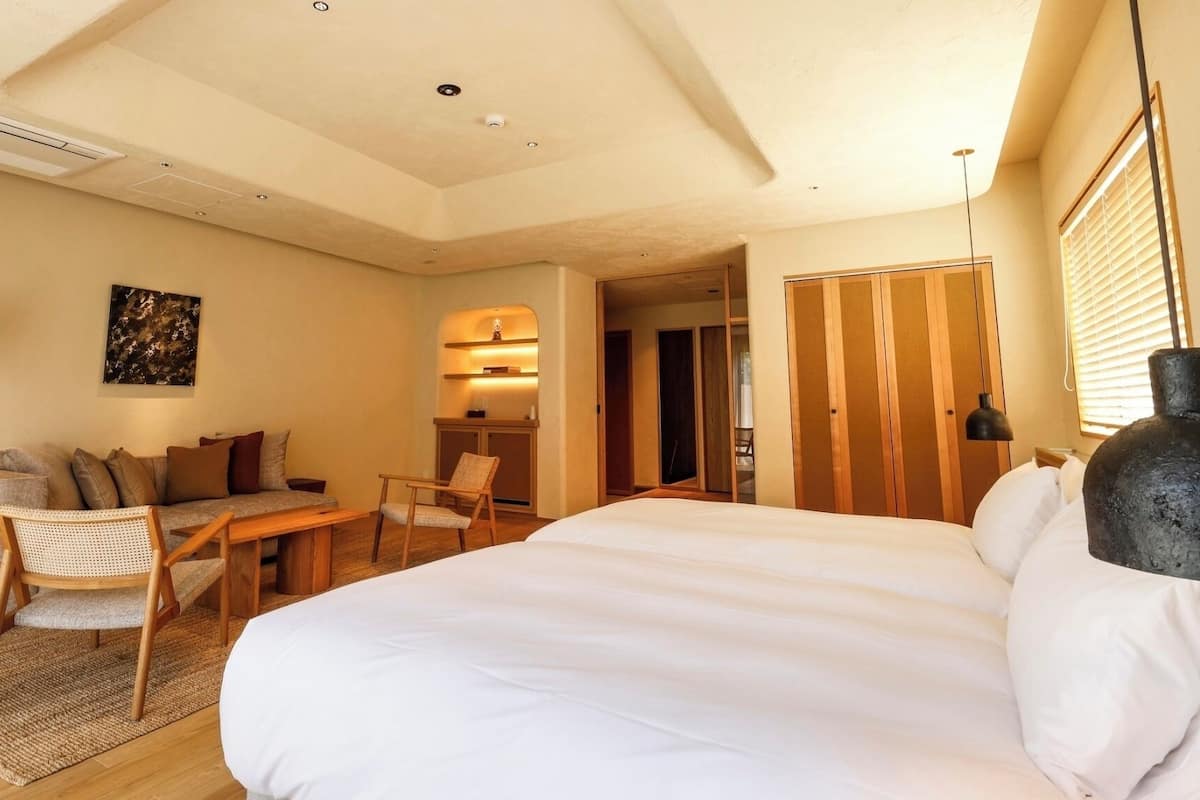 Une chambre d’hôtel comprenant un lit, un canapé, un bureau, une chaise, une lampe et une armoire.