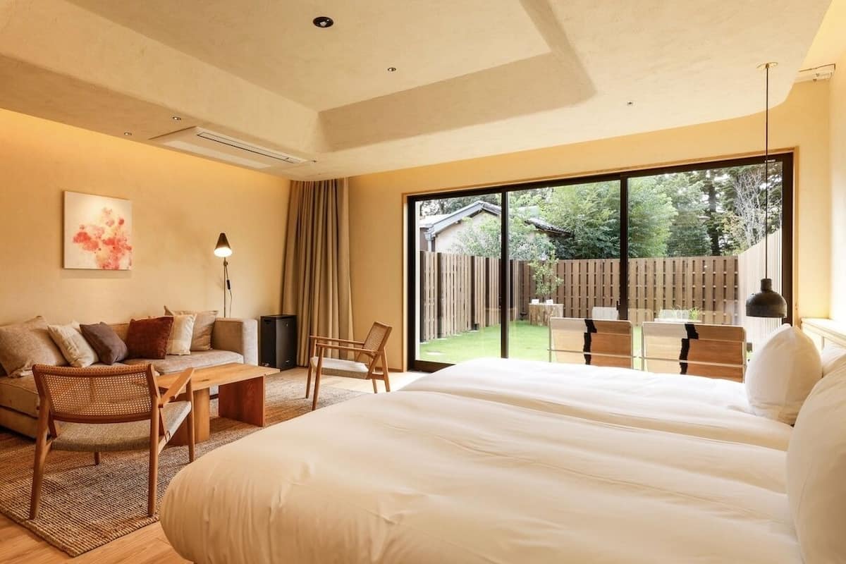 Une chambre d’hôtel moderne dotée d’un grand lit, d’un canapé, d’une table à manger et offrant une vue sur l’espace extérieur.