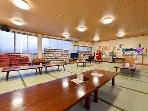 Une bibliothèque avec des tables en bois, des étagères et des tatamis.