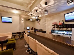 Eine moderne Bar mit Sitzgelegenheiten, einer Theke und einem Fernsehbildschirm.