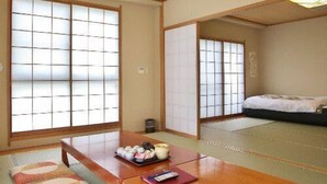 A traditional Japanese room with tatami flooring, sliding doors, a wooden table with cushions, and a bed with a futon. - Susono Tansan Karushiumu Onyoku Inchinose (Susono)