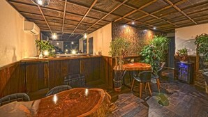 Un interior de restaurante con vigas de madera en el techo, una zona de bar y varias mesas con sillas.