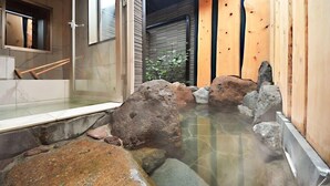 Un área de aguas termales con rocas y una pared de madera.