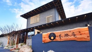 Un edificio con un letrero de madera que muestra caracteres japoneses y el nombre 'SHUNTOU-AN'.