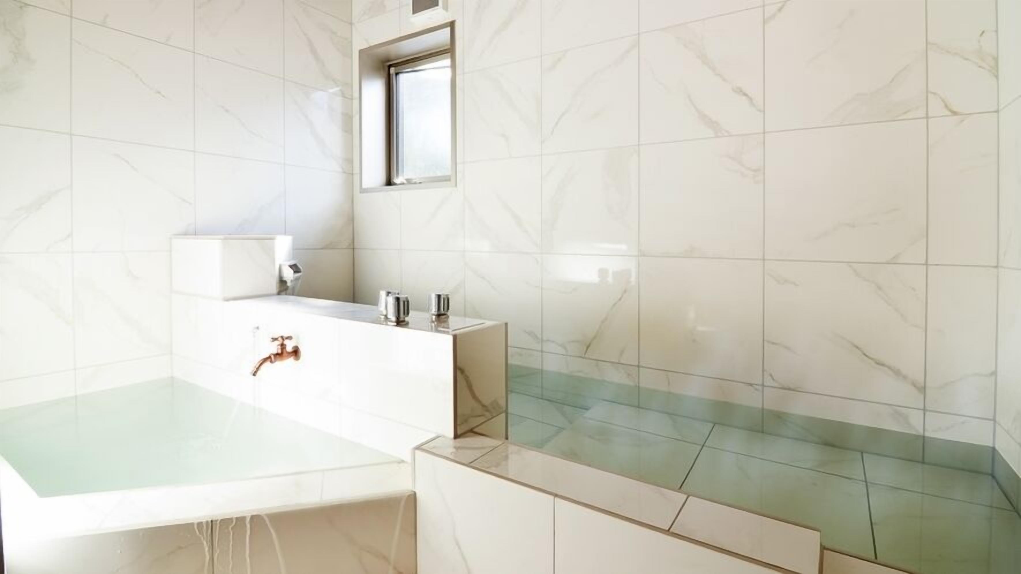 Un baño con bañera, lavamanos, espejo y ventana.