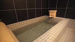A bathtub with a wooden side and a tiled surround. - Kohanso (Isumi)
