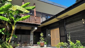 A modern building with a wooden exterior, a balcony, and various potted plants. - Kohanso (Isumi)