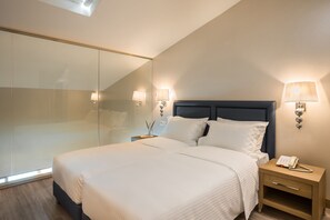 Una habitación de hotel moderna con una cama grande, lámparas de noche, una mesita de noche y una pared divisoria de vidrio.