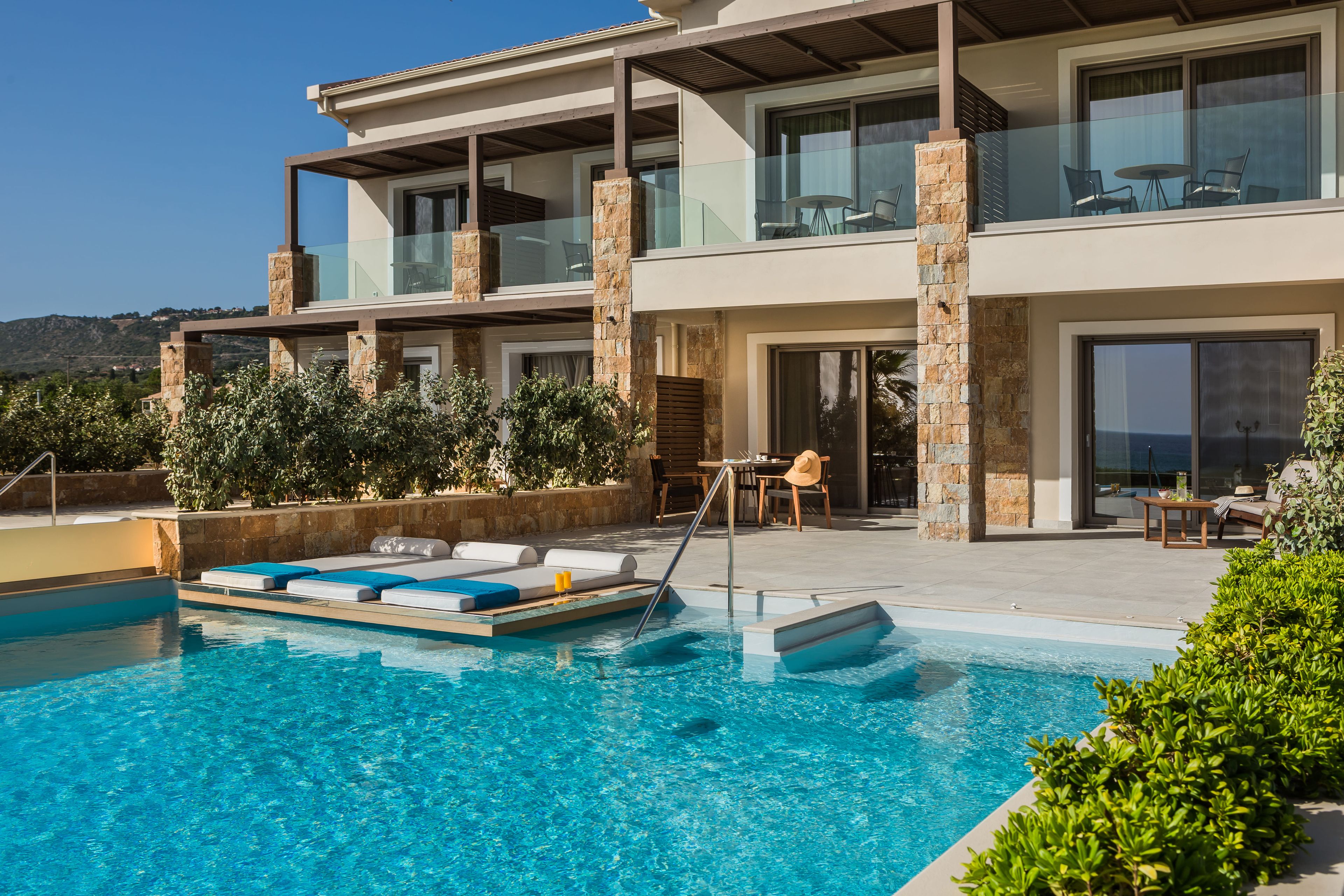 Un edificio moderno de dos pisos con piscina, mobiliario exterior y vistas al paisaje.