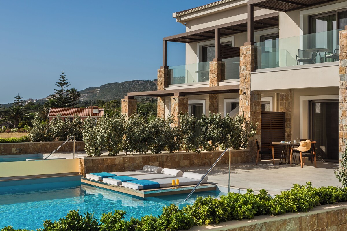 A modern two-story house with a swimming pool, outdoor seating, and a view of the hills.