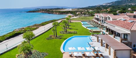 Een resort met een zwembad, ligbedden en uitzicht op zee.