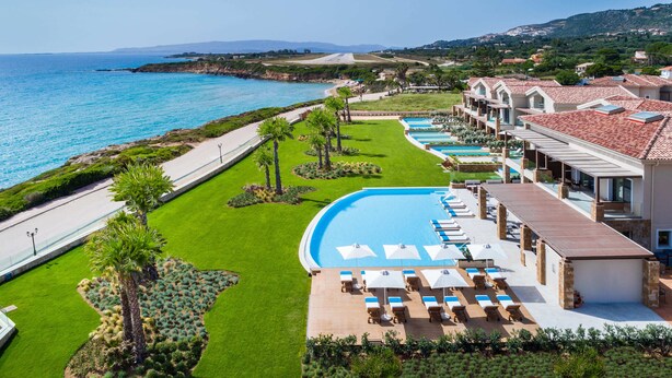 Un complexe hôtelier doté d’une piscine, de chaises longues et offrant une vue sur la mer.