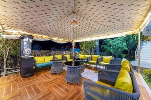 An outdoor patio with a patterned ceiling, a water dispenser, and seating with yellow cushions. - Alaya Stays By Elivaas Kingdom Heartz (Nainital)