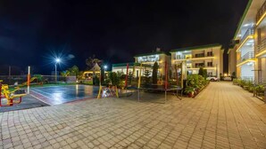 A well-lit outdoor area with a basketball court, a trampoline, and a playground. - Alaya Stays By Elivaas Kingdom Heartz (Nainital)