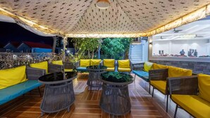 An outdoor seating area with yellow cushions and wicker furniture, under a patterned canopy. - Alaya Stays By Elivaas Kingdom Heartz (Nainital)